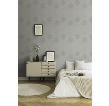 Chambre avec papier peint gris, commode et lit.