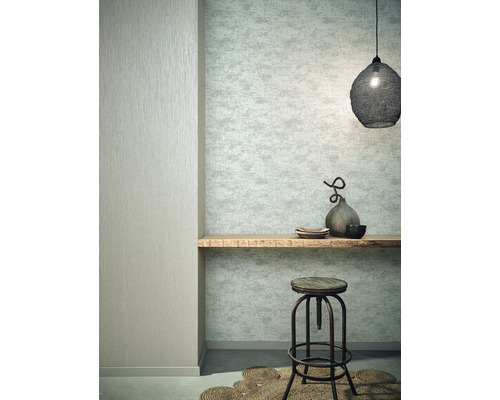 Wohnraum mit gemusterter Tapete, Holzbrett, Hocker und Dekoration