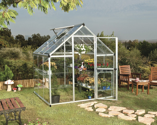 Serre avec plantes et porte ouverte dans le jardin.