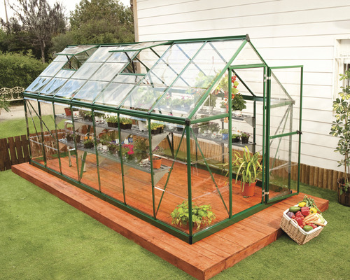 Serre avec étagères, plantes et fenêtres ouvertes sur une terrasse en bois