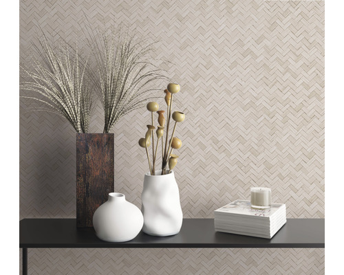 Scène décorative avec des vases, des plantes ornementales, une bougie et des livres sur une étagère devant un mur à motif à chevrons.