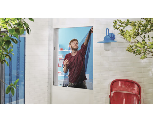 Mann befestigt ein Insektenschutzgitter an einem Fensterrahmen.