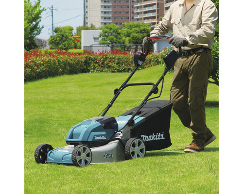 Eine Person benutzt einen Makita Rasenmäher auf einer Rasenfläche.
