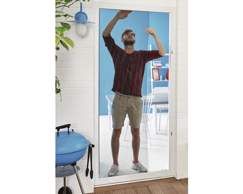 Un homme installe une moustiquaire sur une porte de terrasse. Un barbecue et des meubles de jardin sont visibles à l''arrière-plan.