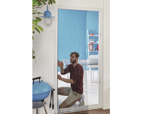 Un homme installe une moustiquaire sur une porte de patio