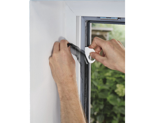 Montage d''une moustiquaire sur un cadre de fenêtre à l''aide d''un outil.