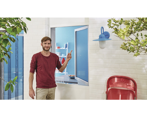 Mann steht vor Fenster mit Insektenschutzgitter, Aussenwandleuchte und Gartenmöbeln