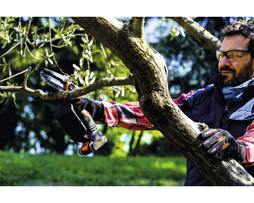 Un homme scie une branche avec une tronçonneuse à batterie