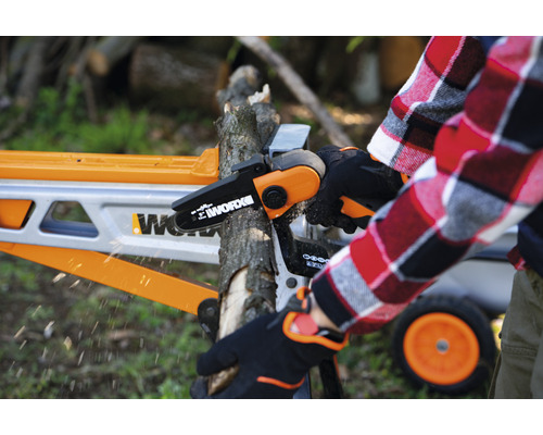 Une personne utilise une tronçonneuse sans fil Worx pour couper une branche sur un chevalet de sciage.