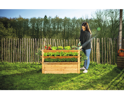 Jardinière en bois surélevée à trois niveaux avec une femme qui jardine