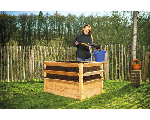 Jardinière surélevée en bois avec trois niveaux et une femme qui ajoute de la terre.