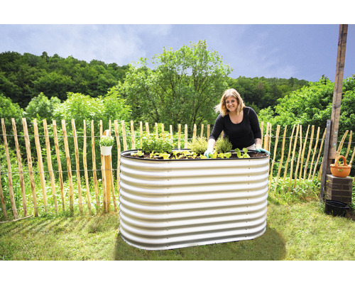 Femme plantant un potager surélevé en métal dans le jardin.