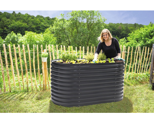 Jardinière surélevée en métal dans le jardin avec une femme jardinant