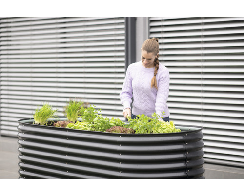 Jardinière surélevée en métal avec plantes et femme faisant du jardinage