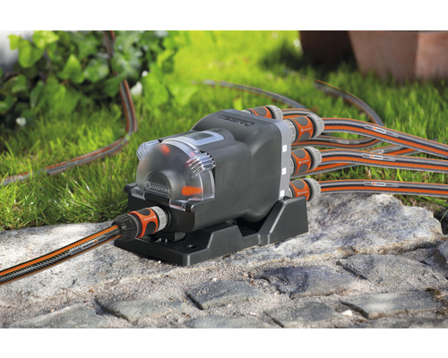 Distributeur d''eau automatique Gardena avec tuyaux d''irrigation sur sol en pierre
