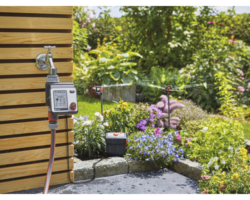 Scène de jardin avec robinet, programmateur d''arrosage et arroseur de pelouse