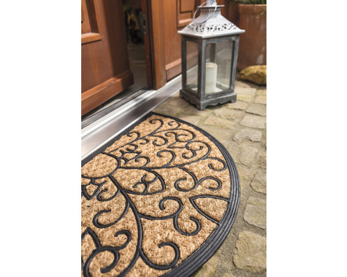 Halbrunde Fussmatte aus Kokosfaser mit floralem Muster vor einer Haustür