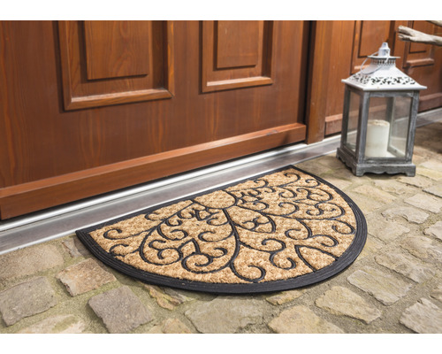 Halbrunde Fussmatte aus Kokosfaser mit dekorativem Muster vor einer Haustür.