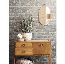 Dekoratives Interieur mit gemusterter Backstein Tapete, Holzkommode, Spiegel und Zimmerpflanze.