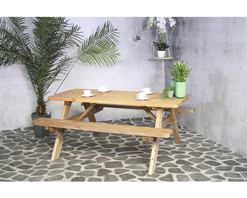 Ensemble de table de pique-nique en bois avec quatre tasses, entouré de plantes.