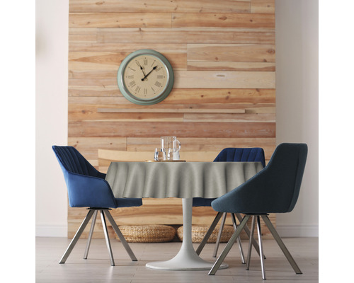 Salle à manger avec table ronde, nappe et chaises devant un mur en bois