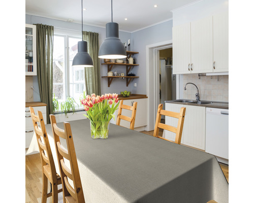 Salle à manger lumineuse avec table en bois, chaises, nappe grise et bouquet de fleurs dans un vase.