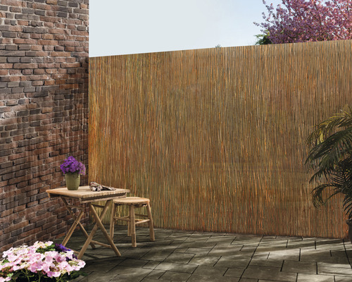 Szene im Freien mit einem Tisch, einem Hocker und einem Sichtschutz aus Naturmaterialien