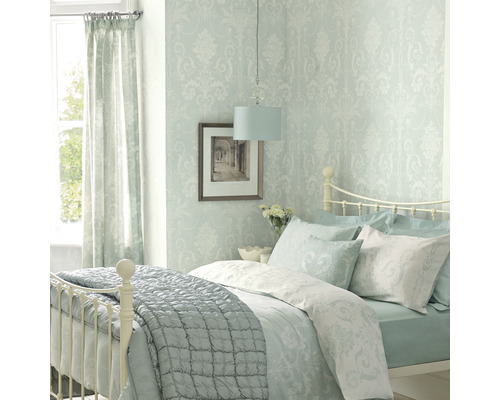 Chambre lumineuse avec lit, papier peint à motifs, rideaux et lampe