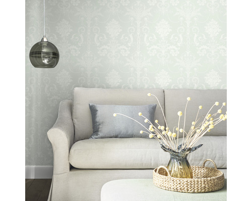 Salon avec papier peint à motifs, canapé, coussin, décoration de table et suspension