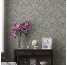 Zimmer mit floraler Tapete, dunklem Holzschrank, Blumen und Dekorationsartikeln