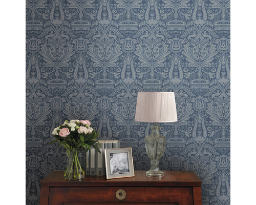 Papier peint décoratif à motifs sur un mur de pièce, table avec lampe, fleurs et cadre photo