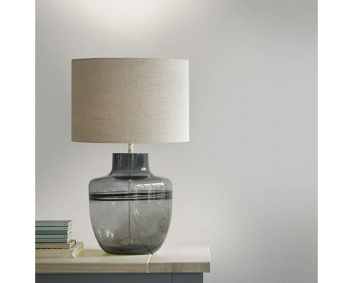 Lampe de table avec abat-jour en tissu et pied en verre sur une table