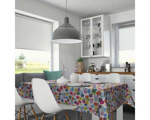 Salle à manger lumineuse avec table, chaises et nappe à pois.