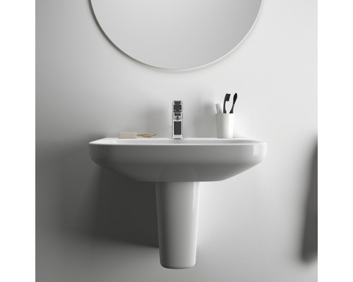 Lavabo en céramique avec robinet, savon, brosses à dents et miroir dans la salle de bain