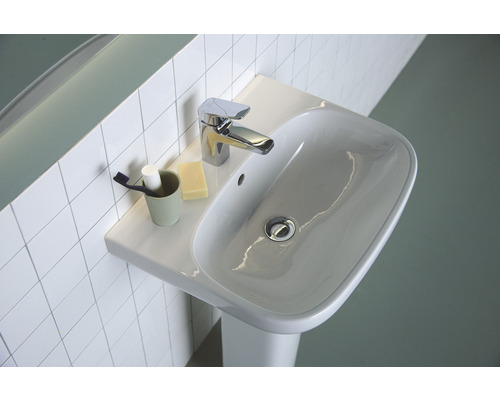 Lavabo avec robinet et accessoires sur étagère devant un mur carrelé