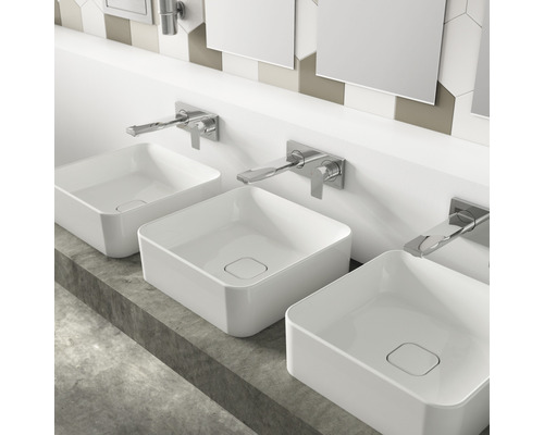 Trois vasques à poser carrées en céramique avec robinetterie sur un plateau en béton