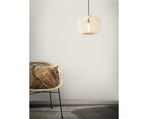 Dekorative Szene mit Rattan-Hängelampe und Sessel mit Kissen