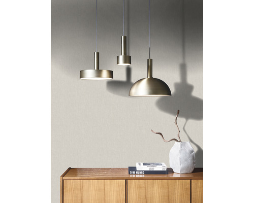 Drei Pendelleuchten aus Metall hängen über einem Holzschrank mit Büchern und einer Vase.