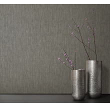 Nahaufnahme einer strukturierten Tapete neben zwei Vasen mit Blütenzweigen.