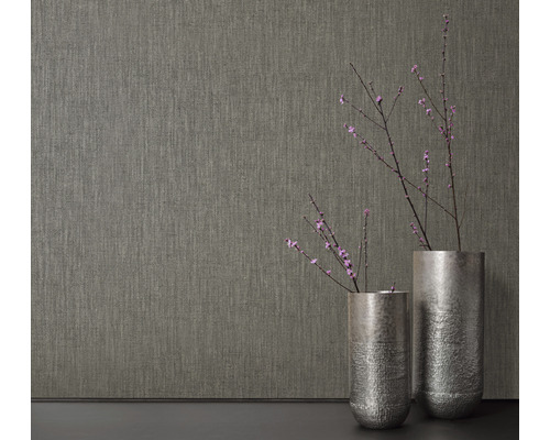 Nahaufnahme einer strukturierten Tapete neben zwei Vasen mit Blütenzweigen.