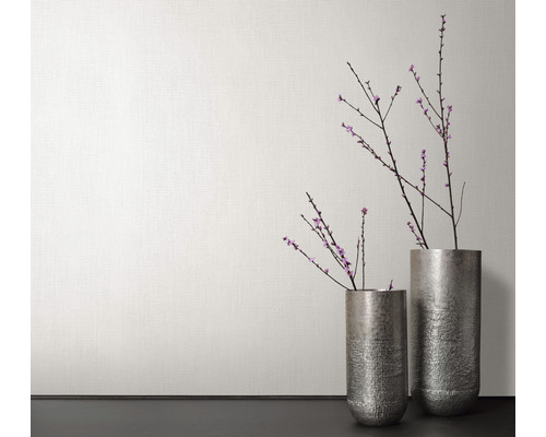 Zwei Metallvasen mit Blütenzweigen vor einer Wand