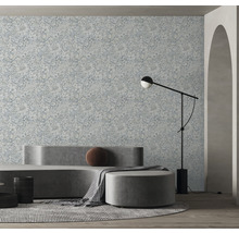 Salon avec papier peint à motifs floraux, canapé, tabouret et lampadaire