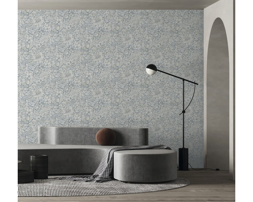 Salon avec papier peint à motifs floraux, canapé, tabouret et lampadaire