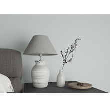 Dekorative Tischleuchte neben Vase und Schale auf einem Nachttisch.