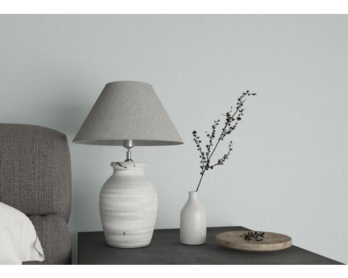 Dekorative Tischleuchte neben Vase und Schale auf einem Nachttisch.