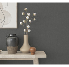 Dekorative Vasen und Pflanzen auf einem hellen Holztisch vor einer grauen Wand.