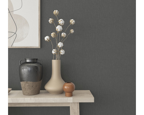 Dekorative Vasen und Pflanzen auf einem hellen Holztisch vor einer grauen Wand.