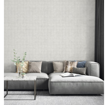 Salon avec canapé gris, coussins et papier peint à motifs pour une ambiance lumineuse et moderne.