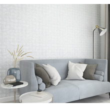 Salon lumineux avec canapé, coussins, tables d''appoint et papier peint à motifs