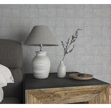 Nature morte décorative avec lampe, vase et bol en bois sur une table de chevet devant un mur texturé